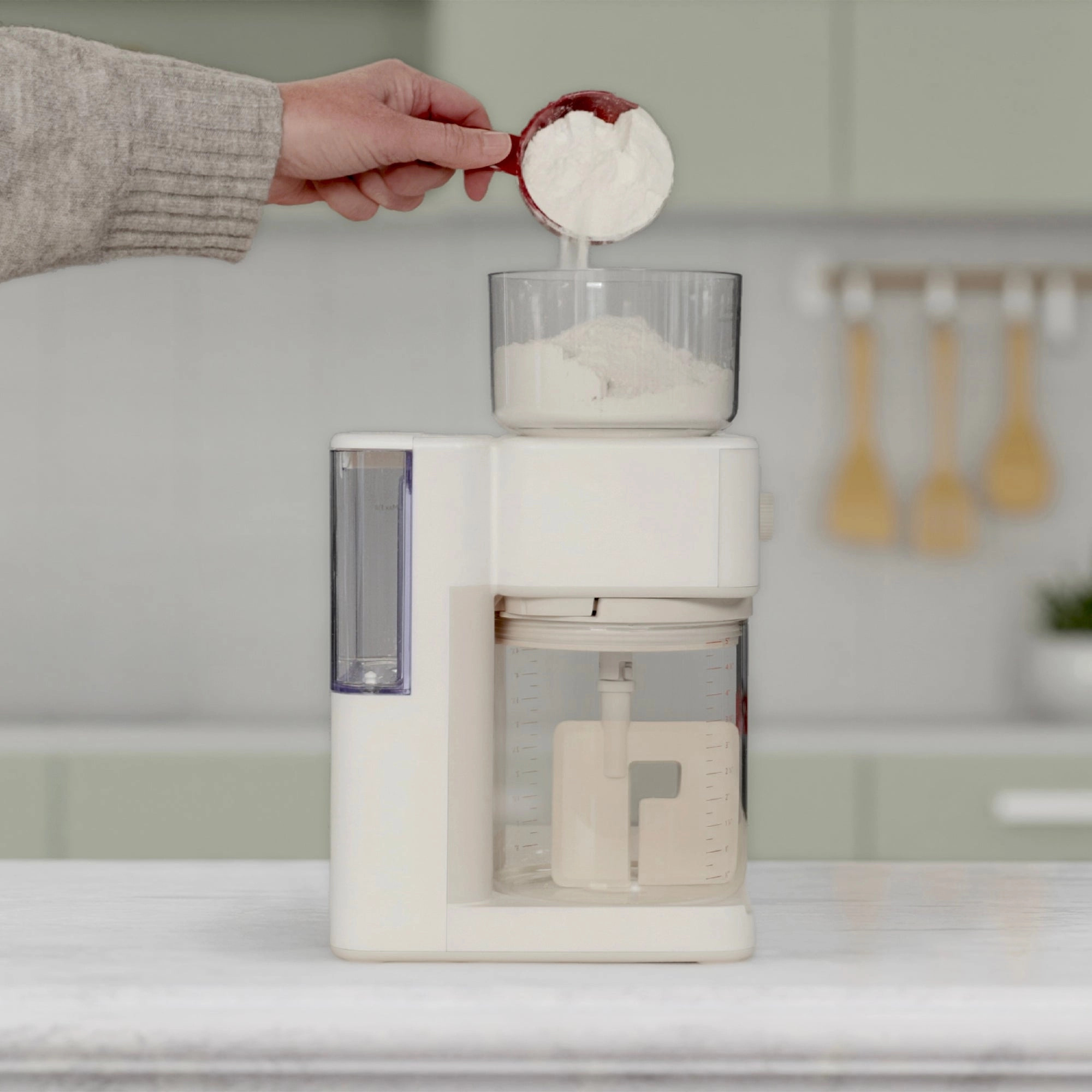 A person adding flour to Sourdough Sidekick in a kitchen