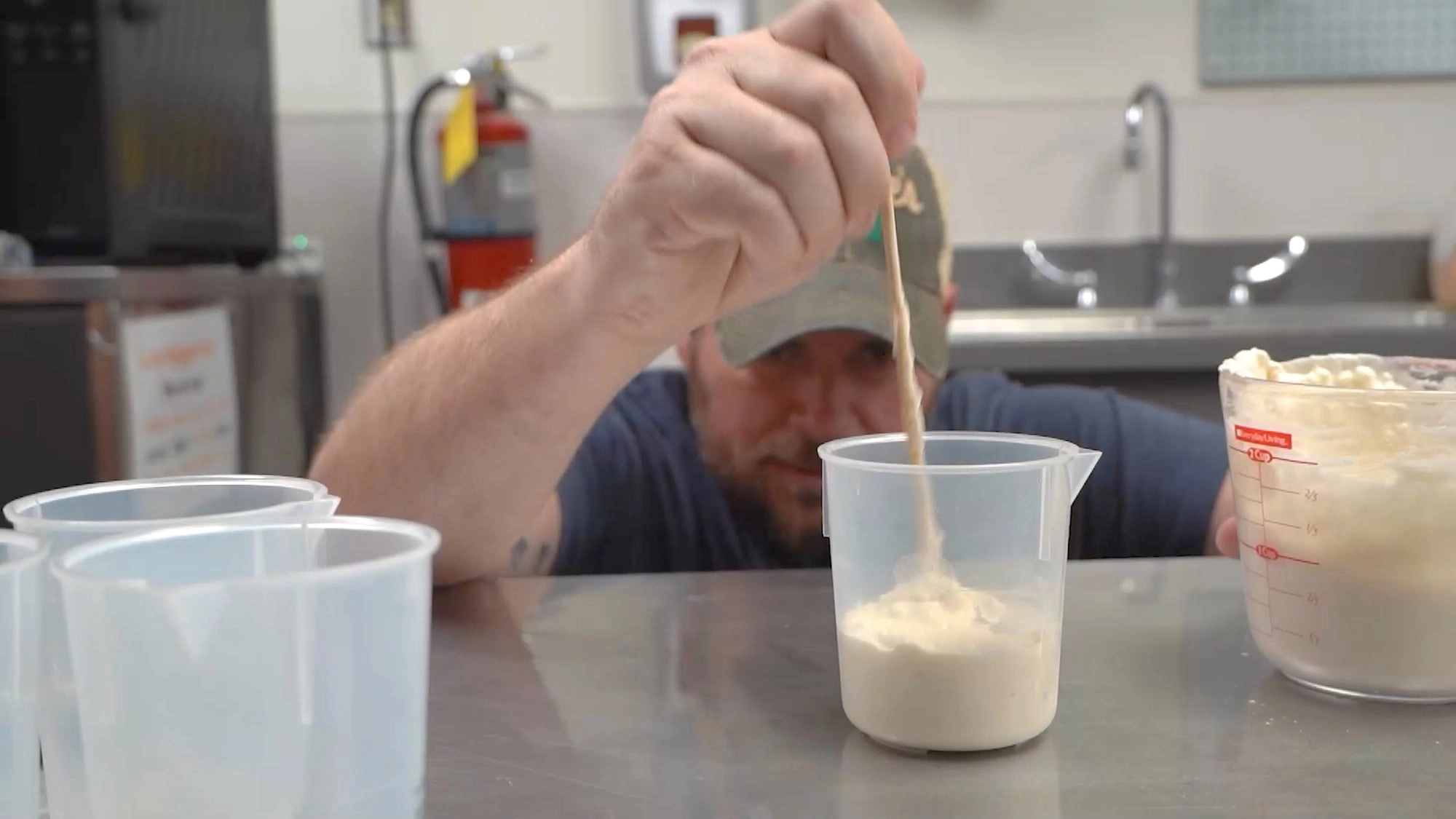 A baker stirring starter in a measuring cup