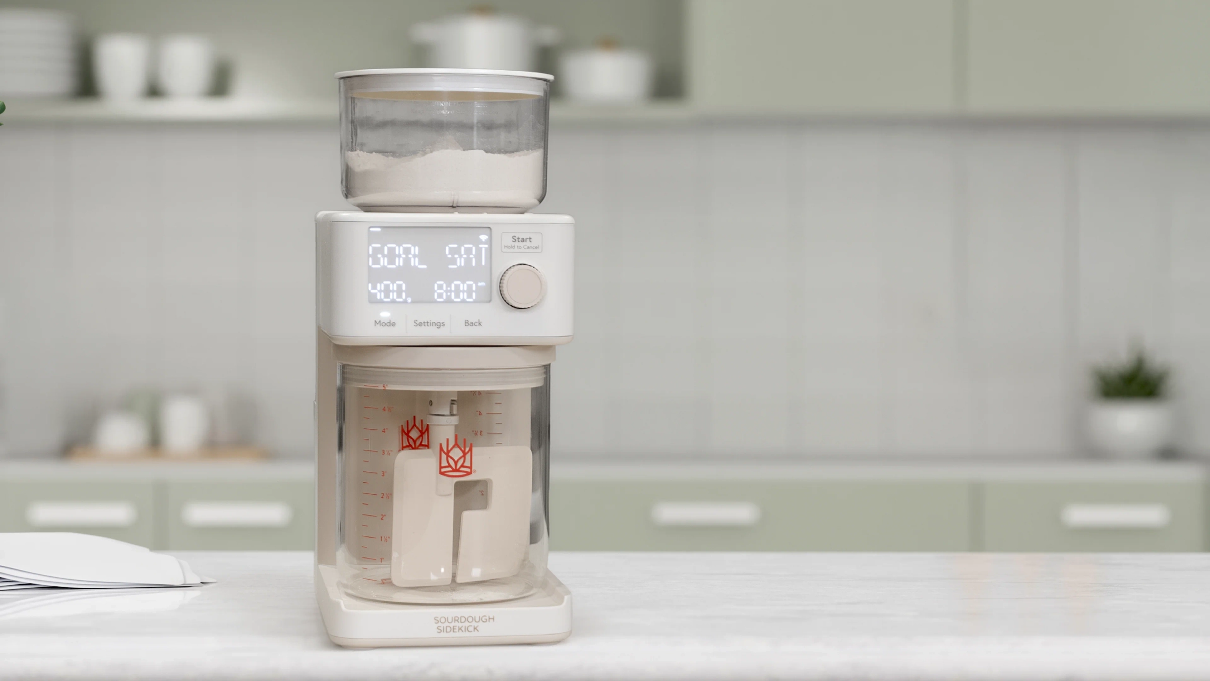 Sourdough Sidekick on a kitchen counter, flour hopper on top and glass crock below